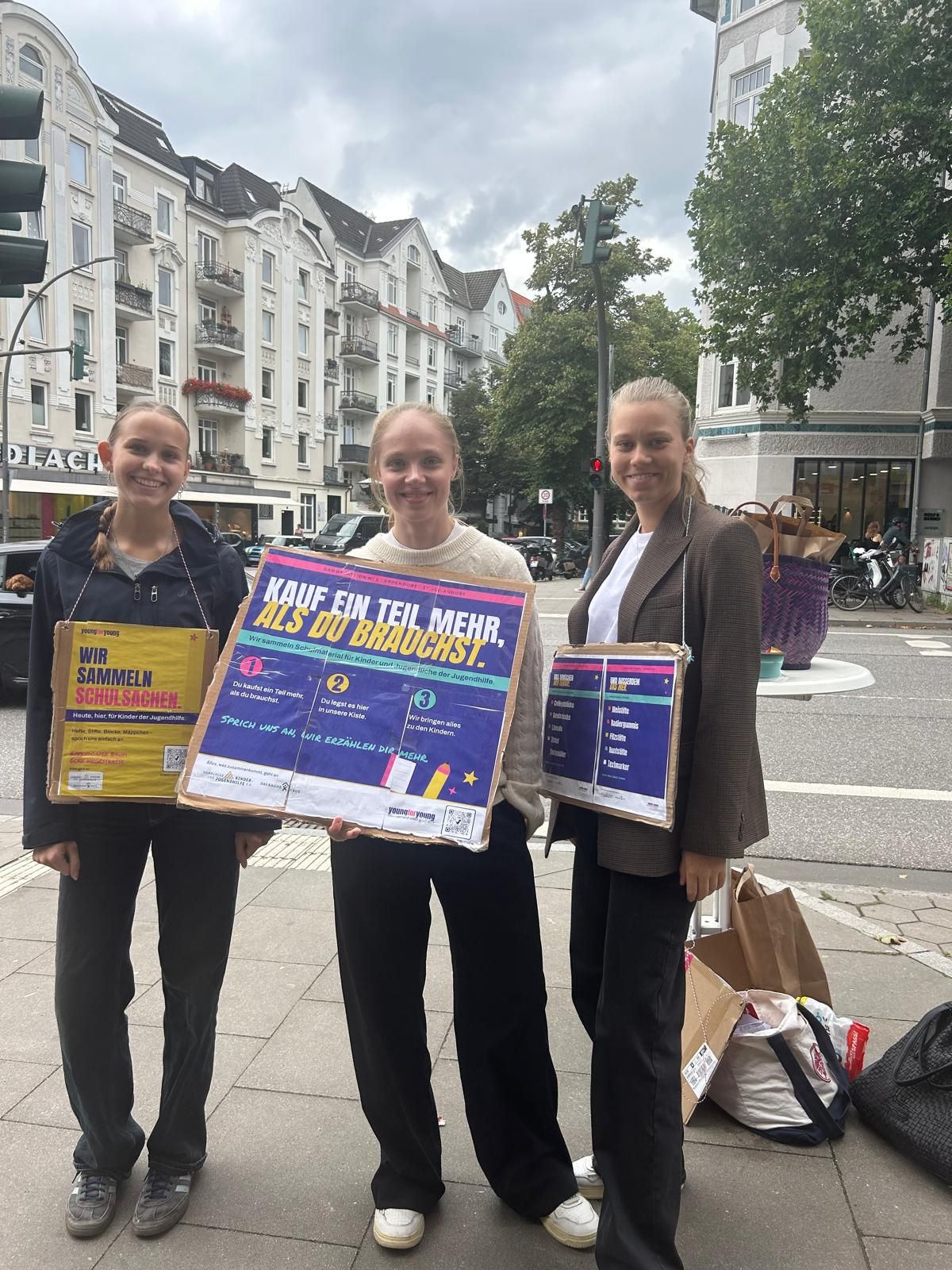 Drei Freiwillige mit Umhängeplakaten an der Kreuzung